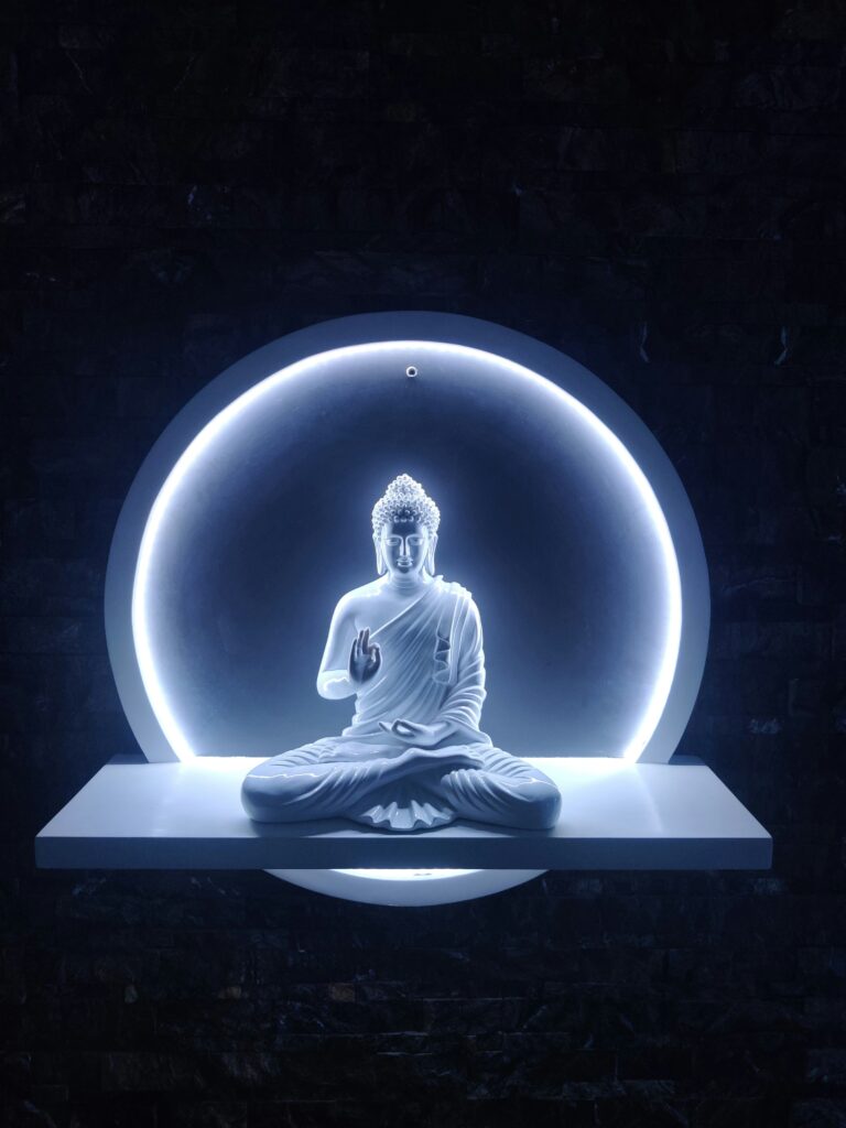 a buddha statue sitting in front of a blue light
