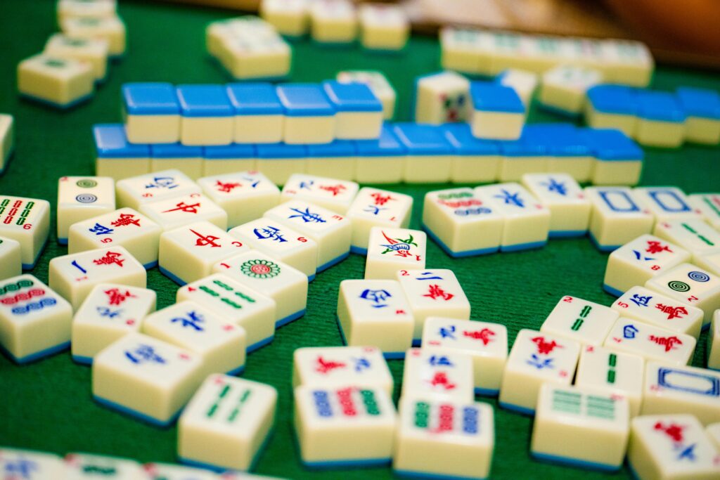 Close-up of colorful mahjong tiles on green felt, showcasing a variety of designs and symbols.