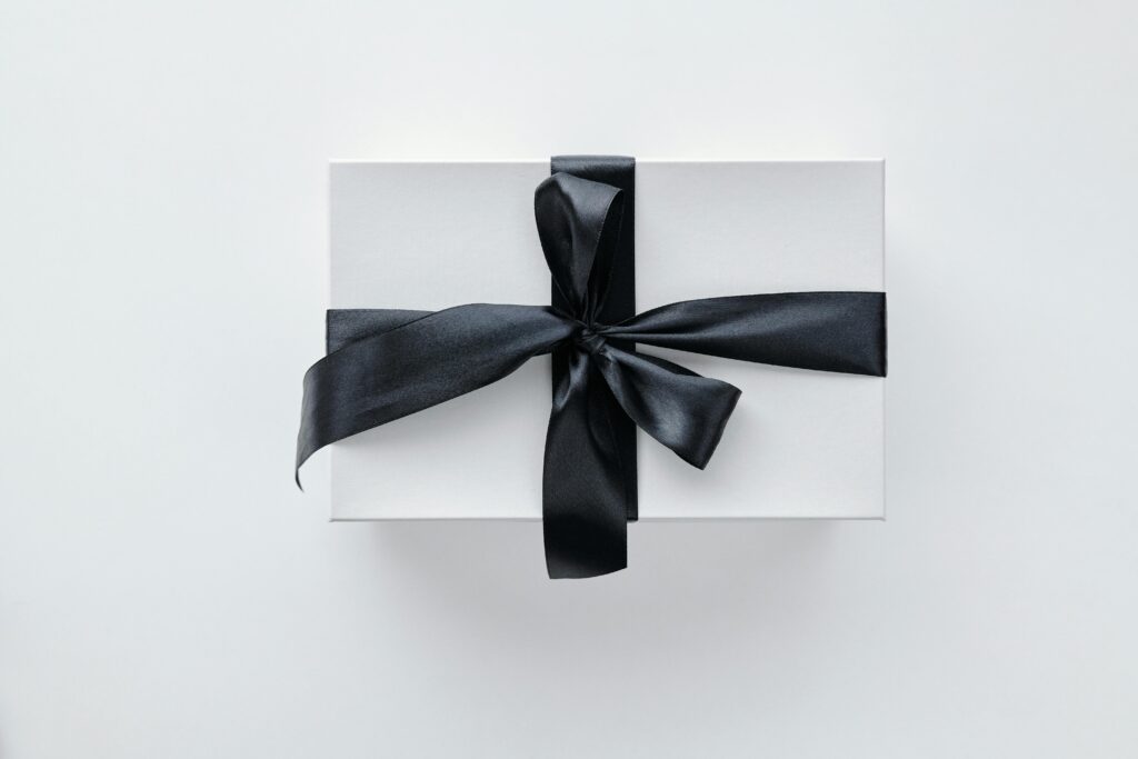 A stylish white gift box adorned with a black satin ribbon on a pure white background.