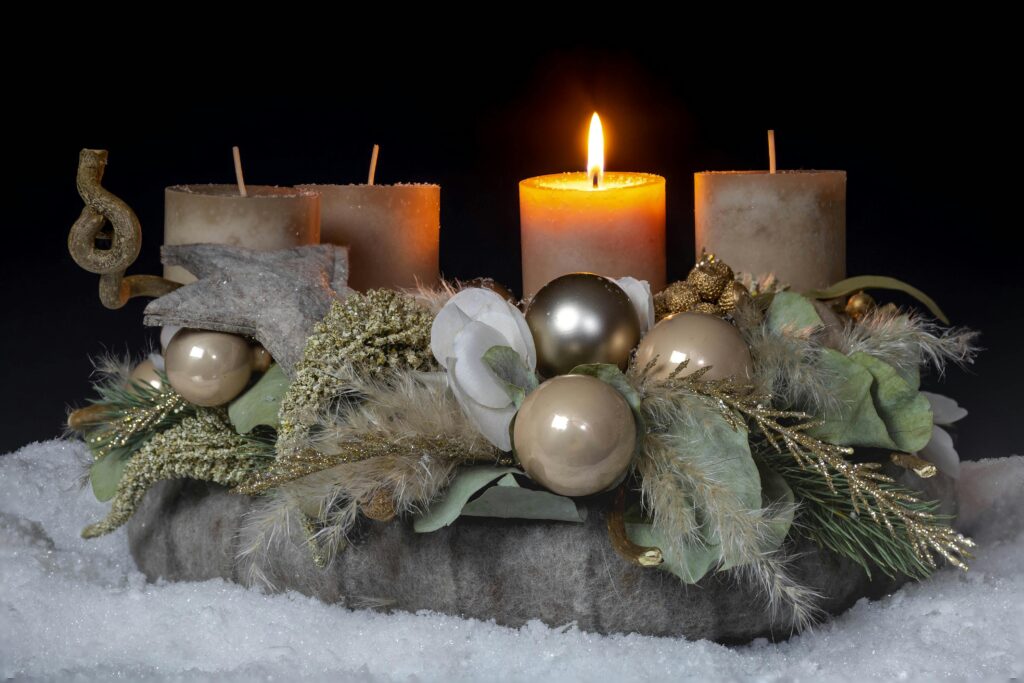 A festive Christmas centerpiece with candles, baubles, and wreaths on snow.