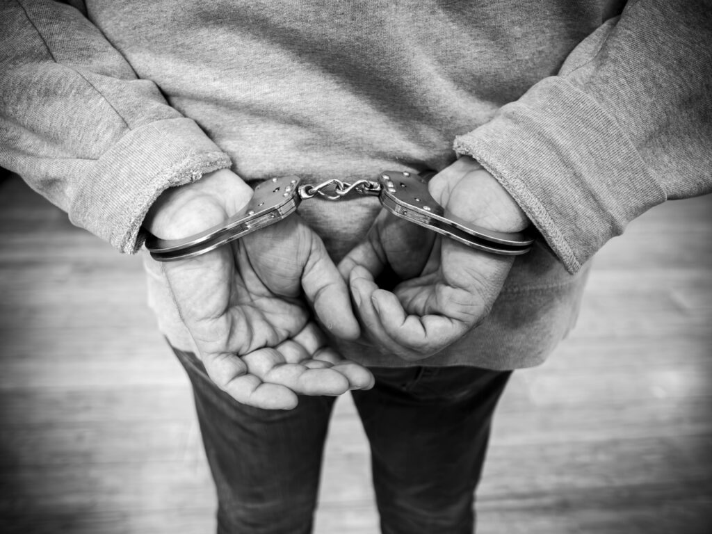 Rear view of a man in handcuffs, captured in monochrome.